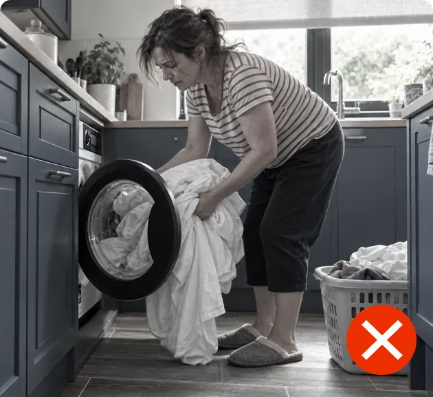 Woman loading sheets into a washing machine